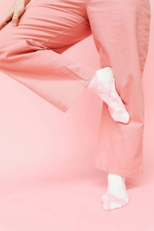 a woman in a white top and pink pants, by Rachel Reckitt, trending on unsplash, arabesque, her foot sticking out, wearing a light - pink suit, made of lab tissue, plain background