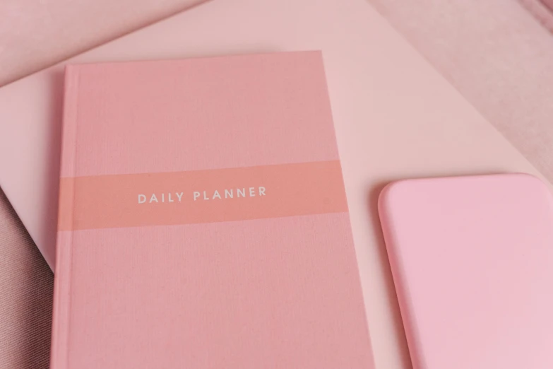 a pink notebook sitting on top of a table next to a pink phone, by Emma Andijewska, trending on unsplash, minimalism, planner stickers, detail shot, with two front pockets, designed in blender