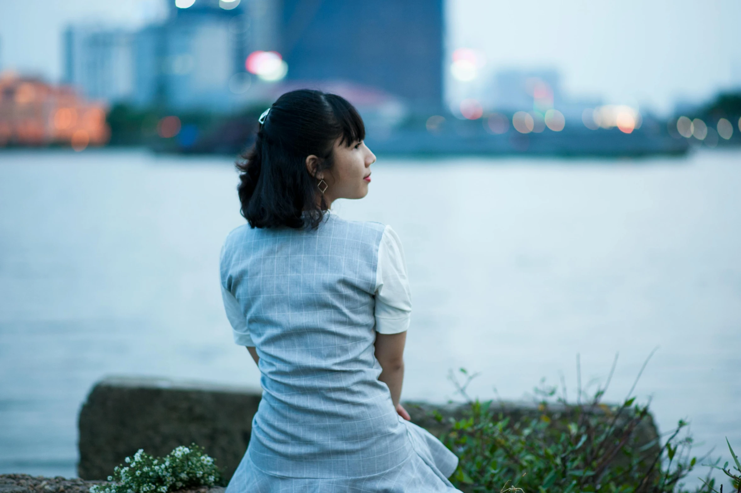 a little girl sitting next to a body of water, a picture, inspired by Cui Bai, unsplash, looking over city, handsome girl, late summer evening, sakimichan hdri