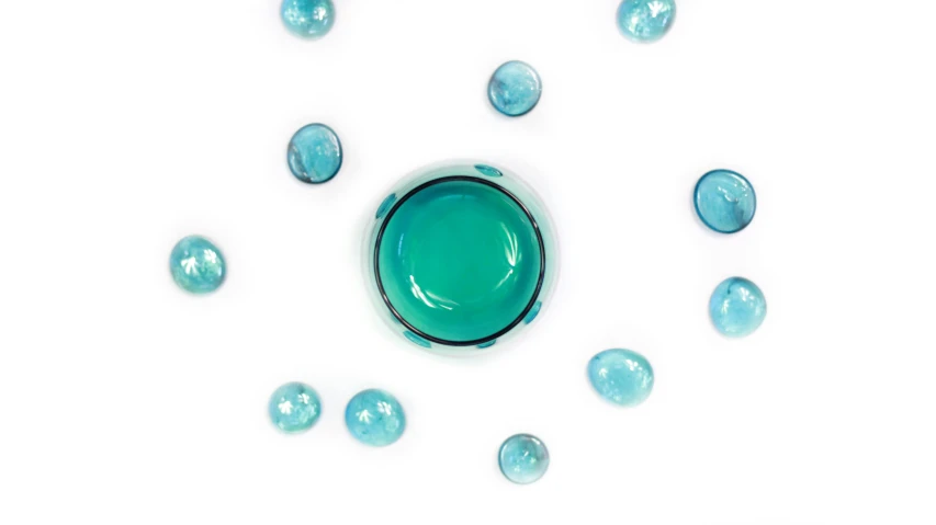 a close up of a bowl of paint on a white surface, inspired by Damien Hirst, unsplash, teal lights, glass spheres, skincare, jade green