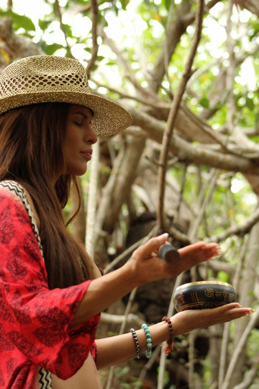 a woman in a hat holding an object in her hand, pandora jungle, tanned ameera al taweel, feeling the nature, performing