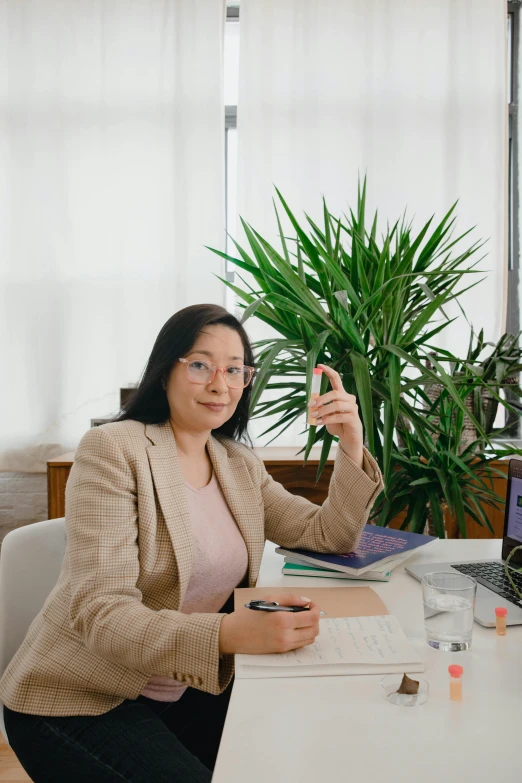 a woman sitting at a desk in front of a computer, by helen huang, holding a staff, next to a plant, ceo, with index finger