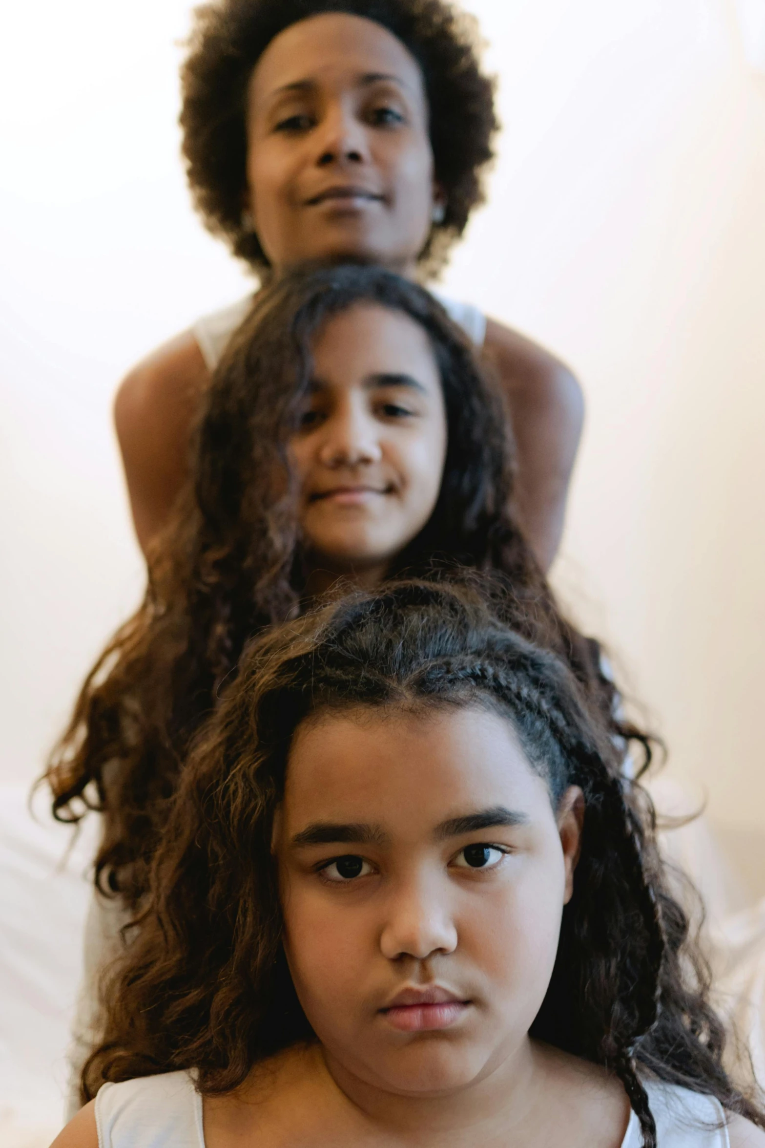 a group of women sitting on top of a bed, an album cover, by Nadir Afonso, unsplash, hurufiyya, close up head shot, kids, three heads, clumps of hair