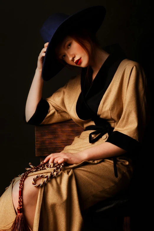 a woman sitting in a chair with a hat on, a portrait, inspired by Jean-Jacques Henner, trending on pexels, classy yukata clothing, ginger. art nouveau, 1930s style clothing, brown robes