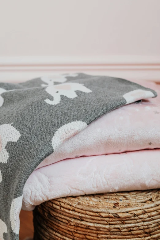 a pile of blankets sitting on top of a wicker basket, pink and grey clouds, detailed product image, boys, detail shot