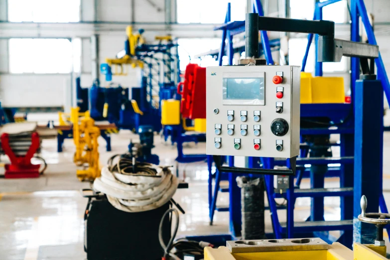 a machine that is sitting inside of a building, unsplash, blue theme and yellow accents, factory floor, cables hanging, worksafe. instagram photo