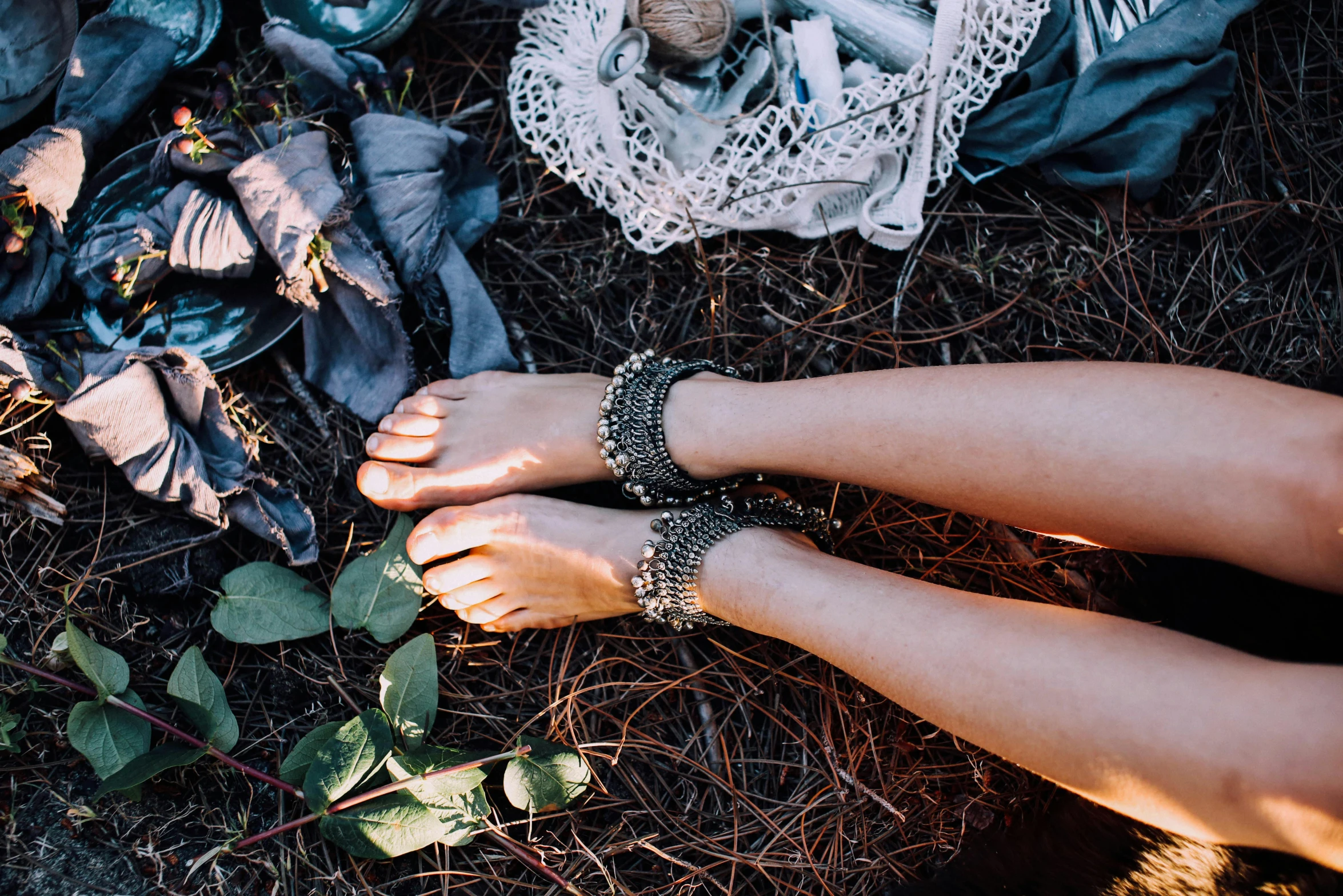 a close up of a person's feet on the ground, inspired by Elsa Bleda, trending on pexels, cottage hippie naturalist, silver accessories, garters, covered in plants