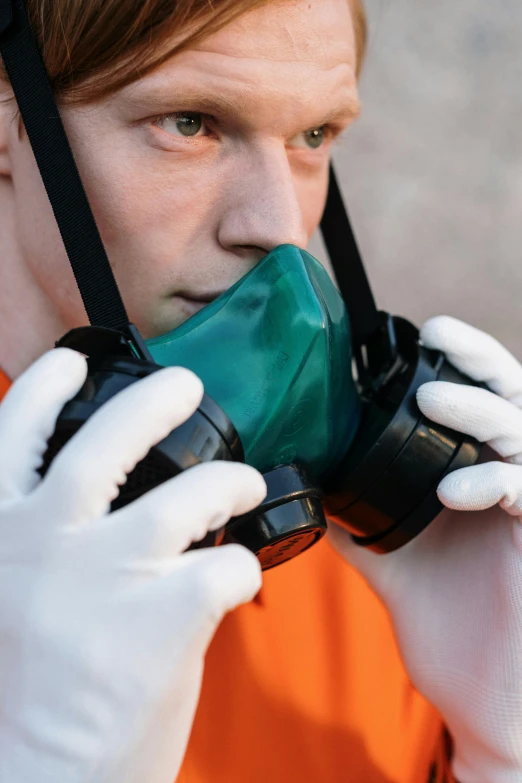 a man in an orange shirt and white gloves talking on a cell phone, shutterstock, plasticien, gasmask, portait image, green facemask, a high angle shot