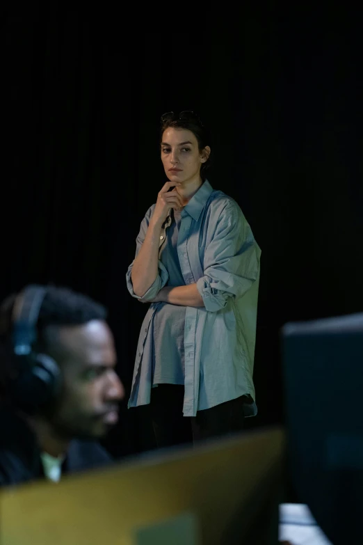 a woman standing in front of a computer screen, an album cover, inspired by Elsa Bleda, pexels, realism, gaming headset, meet the actor behind the scenes, serious expression, sitting at a control center