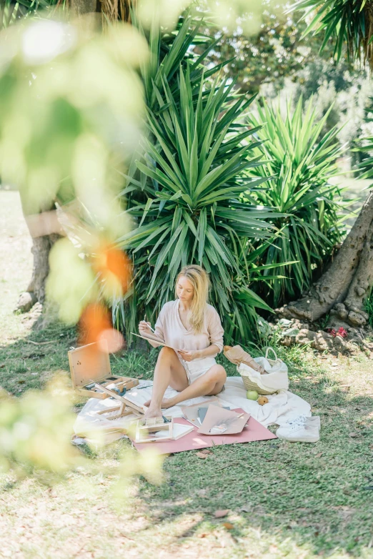 a woman sitting on a blanket in the grass, eating a cheese platter, sitting under a tree, sol retreat, blonde women