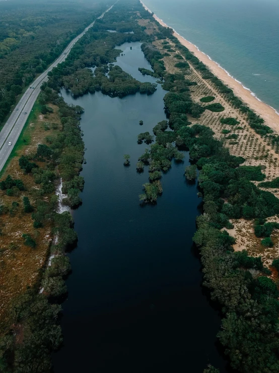 a large body of water next to a sandy beach, by Adam Marczyński, pexels contest winner, hurufiyya, road into the forest with a lake, bird\'s eye view, jerez, thumbnail