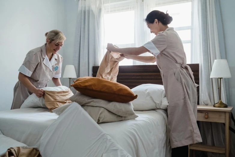 a couple of women standing next to each other on a bed, nurse scrubs, inspect in inventory image, brown, warm sunshine