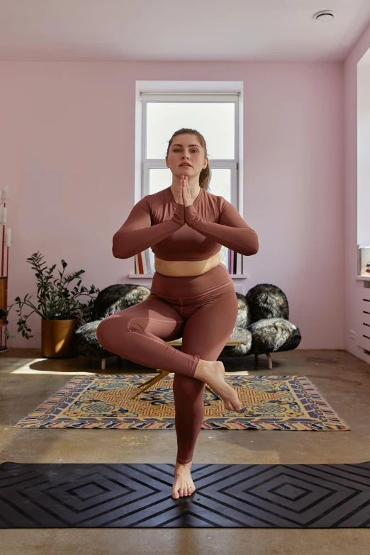 a woman doing a yoga pose in a pink room, a statue, inspired by Louisa Matthíasdóttir, wearing a tracksuit, brown, lotus pose, leggings