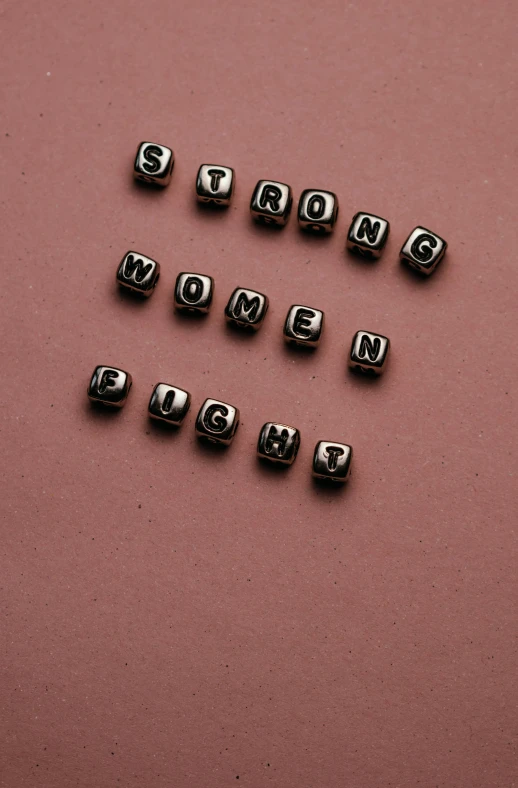 a couple of beads that are on top of a table, an album cover, by Emma Andijewska, trending on pexels, feminist art, strength, - 12p, blocks, typographic