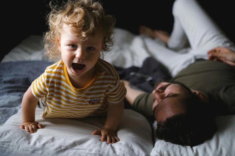 a man laying on top of a bed next to a little girl, pexels contest winner, all overly excited, lachlan bailey, thumbnail, zoomed in