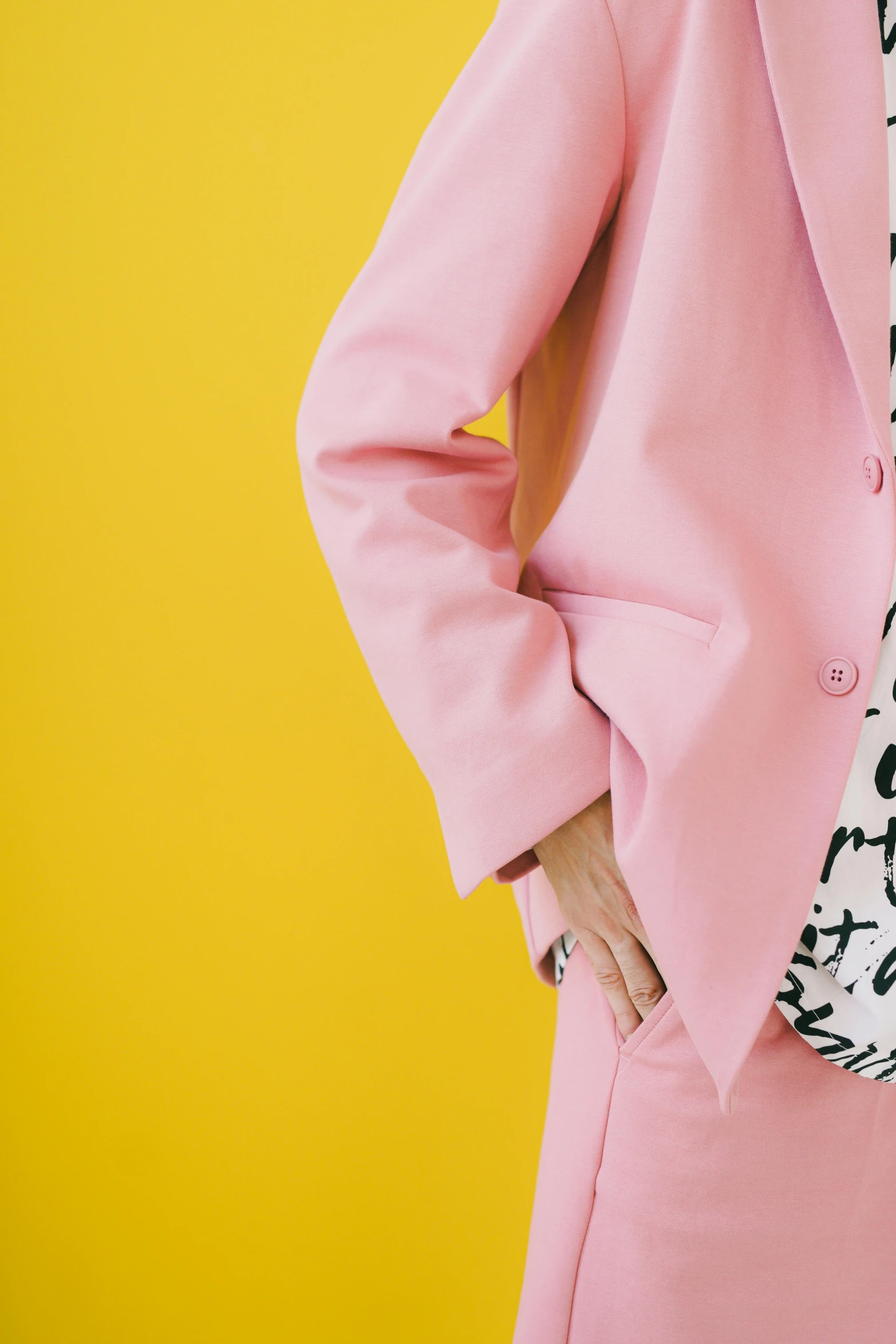 a woman in a pink suit stands against a yellow background, inspired by Peter Alexander Hay, trending on pexels, aestheticism, black white pastel pink, subject detail: wearing a suit, graphic tees, detail shot