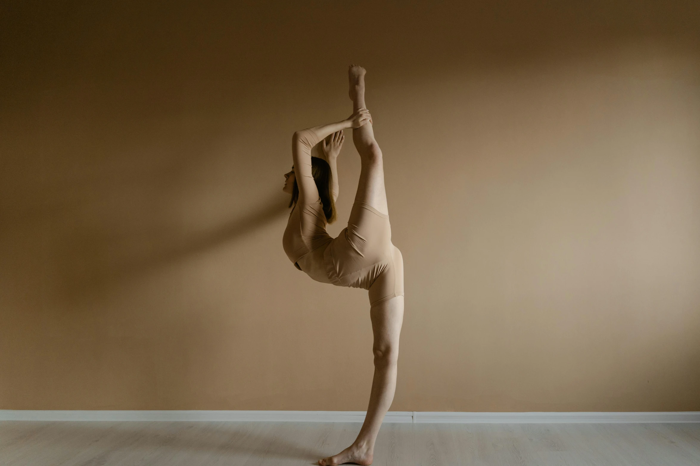 a person doing a handstand on a hard wood floor, by Elizabeth Polunin, pexels contest winner, arabesque, ochre, light tan, full body picture, tights skin