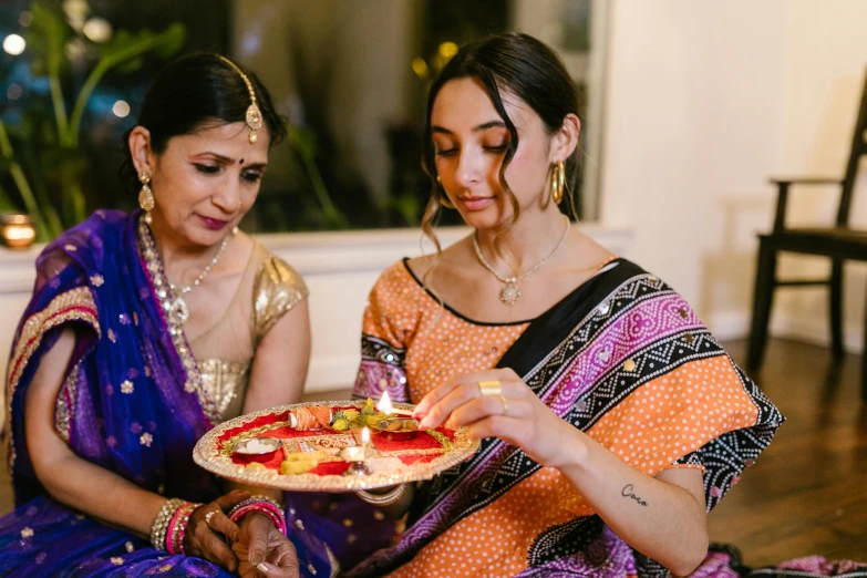 a couple of women sitting next to each other, pexels contest winner, hurufiyya, offering a plate of food, bollywood, decorations, avatar image