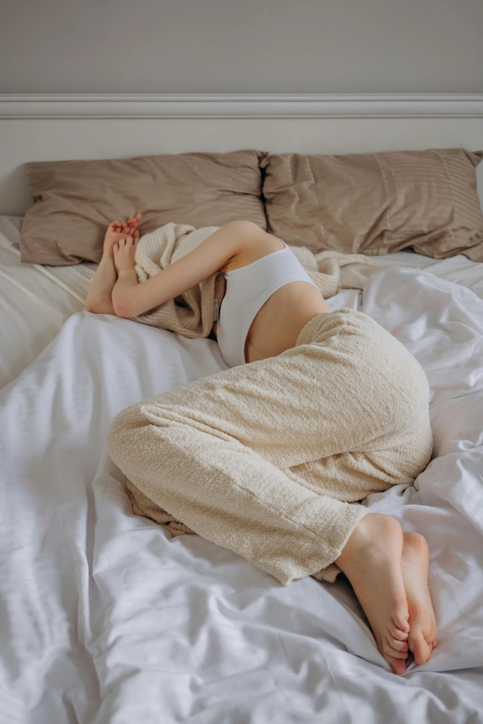 a woman laying on top of a bed covered in white sheets, inspired by Elsa Bleda, reddit, pants, low quality photo, 'i'm so tired, gif