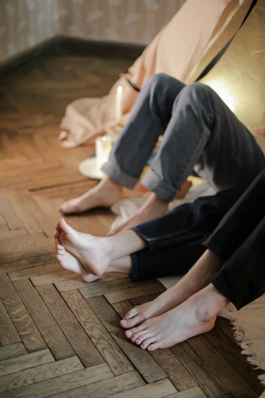 a group of people sitting on top of a wooden floor, sitting on a bed