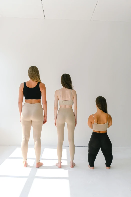 a group of women standing next to each other in a room, inspired by Vanessa Beecroft, trending on unsplash, renaissance, leggings, back view also, three views, neutral colours