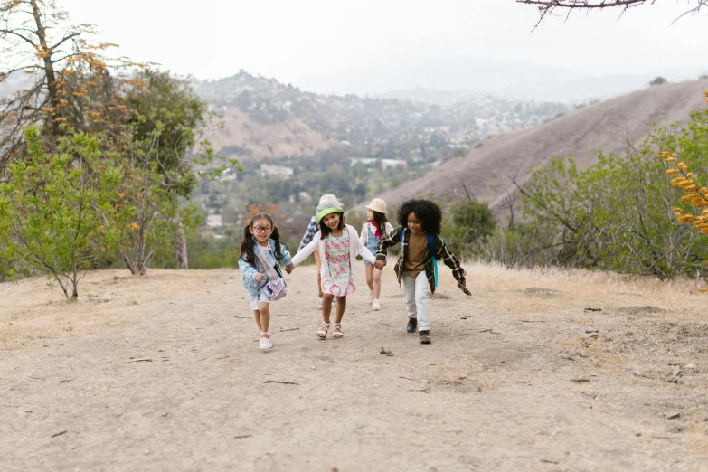 a group of children running down a dirt road, by Winona Nelson, pexels contest winner, mulholland drive, standing on top of a mountain, justina blakeney, walking at the park