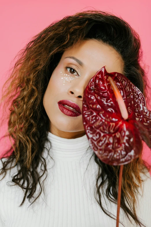 a woman holding a flower in front of her face, an album cover, by Dulah Marie Evans, trending on pexels, renaissance, deep red lips, mixed race, studio shoot, curly haired