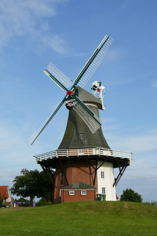 a windmill sitting on top of a lush green field, a picture, by Jan Theuninck, german renaissance architecture, huge!!!, 1km tall, front side