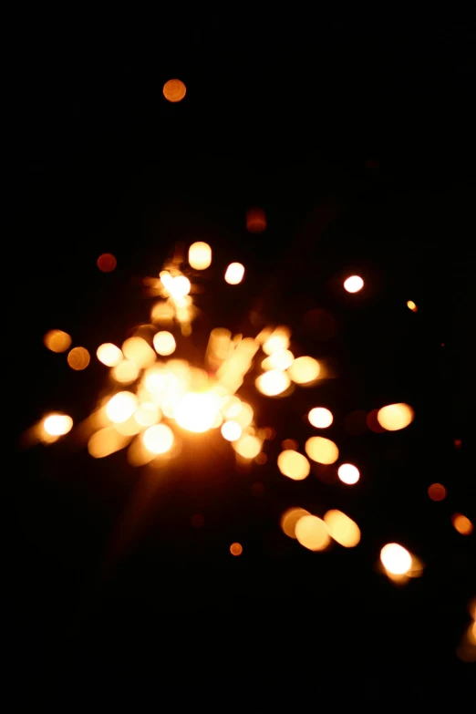 a close up of a sparkler in the dark, taken on an iphone, emitting light ornaments, lit from above, taken on a 2010s camera