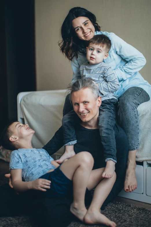 a family sitting on a couch in a living room, by Adam Marczyński, pexels contest winner, soft grey and blue natural light, caring fatherly wide forehead, piled around, non-binary