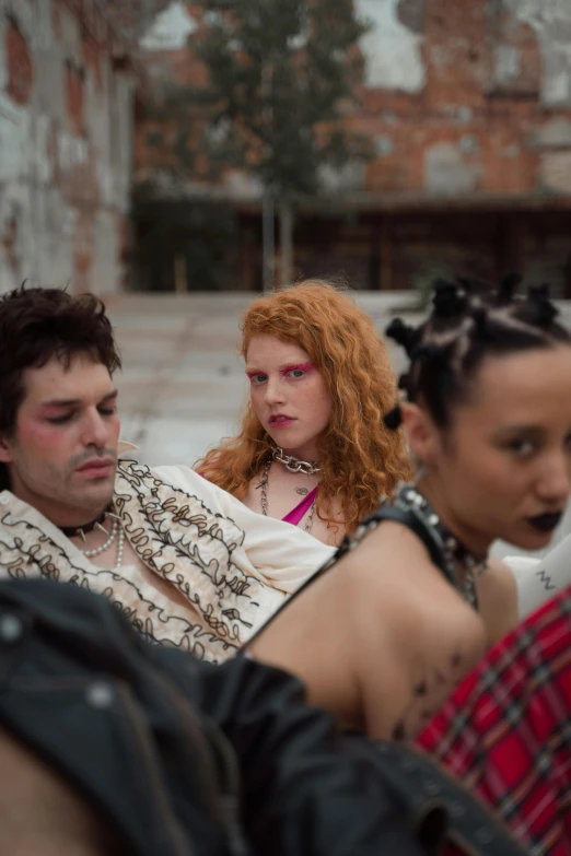 a group of people sitting next to each other, inspired by Nan Goldin, renaissance, dressed in crustpunk clothing, snakes in hair, production photo, young handsome pale roma