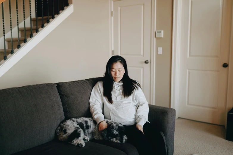 a woman sitting on a couch with a dog, inspired by helen huang, pexels contest winner, slight overcast lighting, avatar image, asian descent, long distance photo