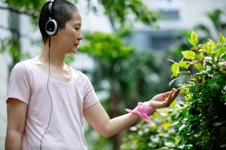 a man standing next to a bush with headphones on, inspired by Song Xu, happening, picking up a flower, ai biodiversity, profile image, asian woman