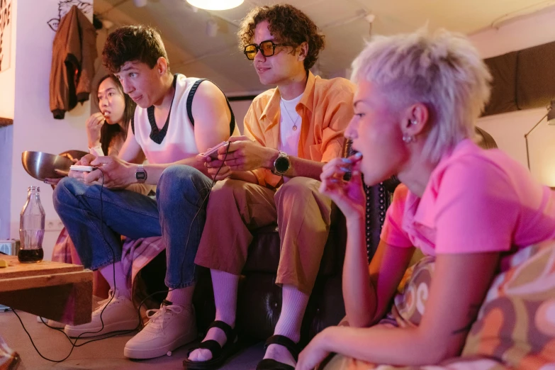 a group of people sitting on top of a couch, a cartoon, inspired by Nan Goldin, pexels, hyperrealism, 8 0 s asian neon movie still, finn wolfhard, playing games, band promo photo