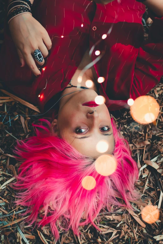 a woman with pink hair laying on the ground, a portrait, inspired by Elsa Bleda, trending on pexels, renaissance, firefly lights, deep red roots, with pop punk style, head straight down