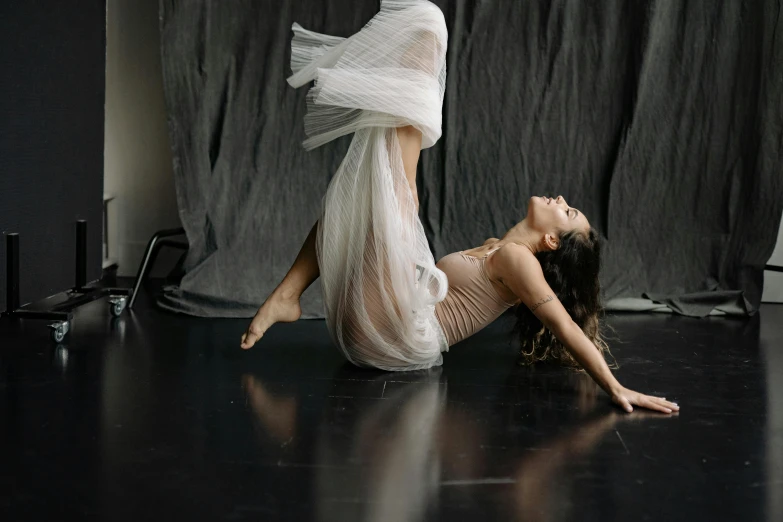 a woman in a white dress laying on the floor, unsplash, arabesque, she is dancing. realistic, bella poarch, studio, sheer