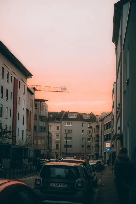 a car driving down a street next to tall buildings, by Tobias Stimmer, pexels contest winner, happening, pink sunset, photo of zurich, low quality photo, a ghetto in germany