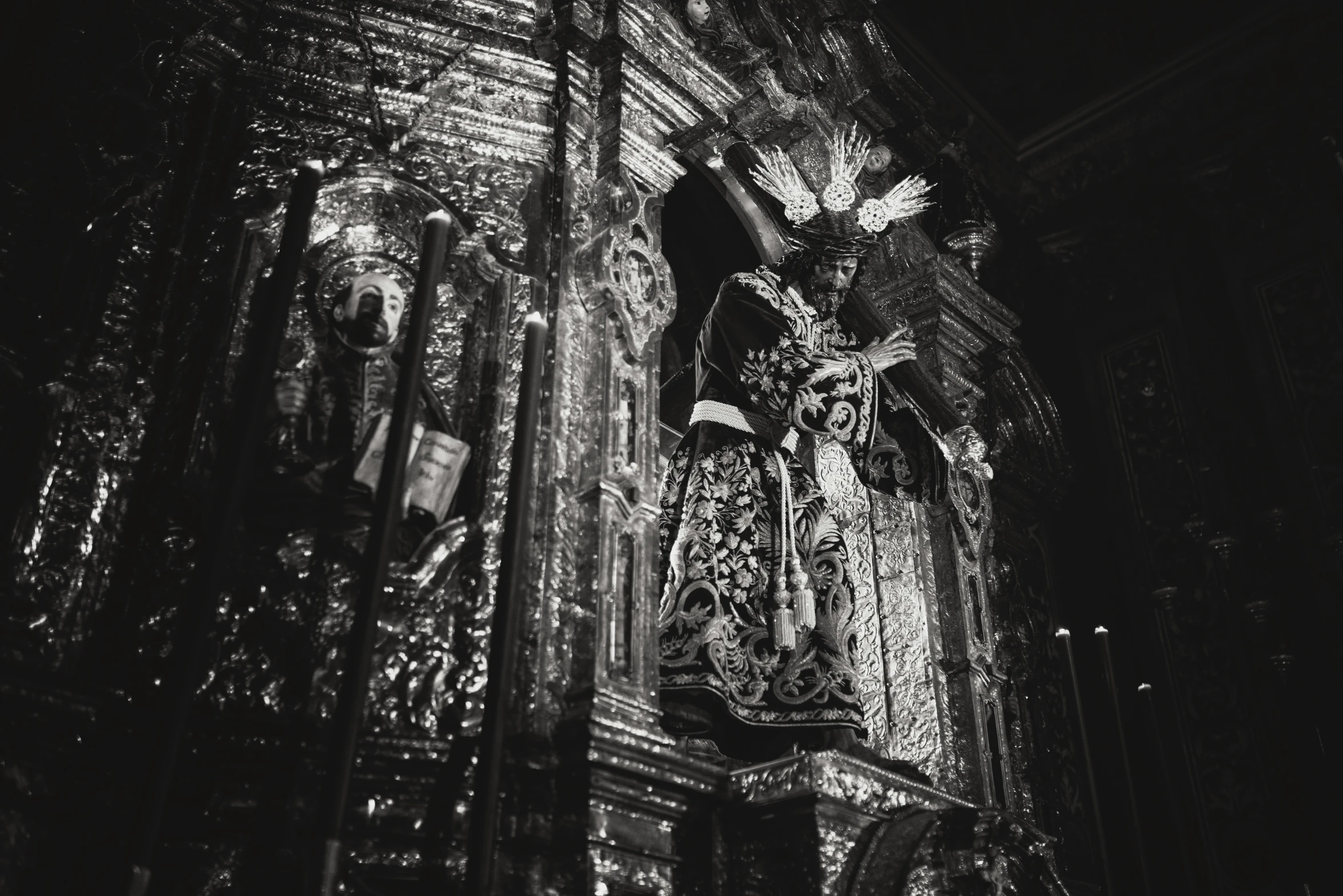 a black and white photo of a statue in a church, by Matteo Pérez, unsplash, made of intricate metal and wood, elaborate cult robes, illuminated, holy ceremony