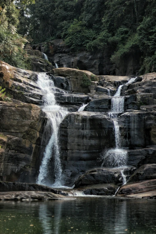 a large waterfall in the middle of a forest, sri lankan landscape, rocky terrain, subtle detailing, highly polished