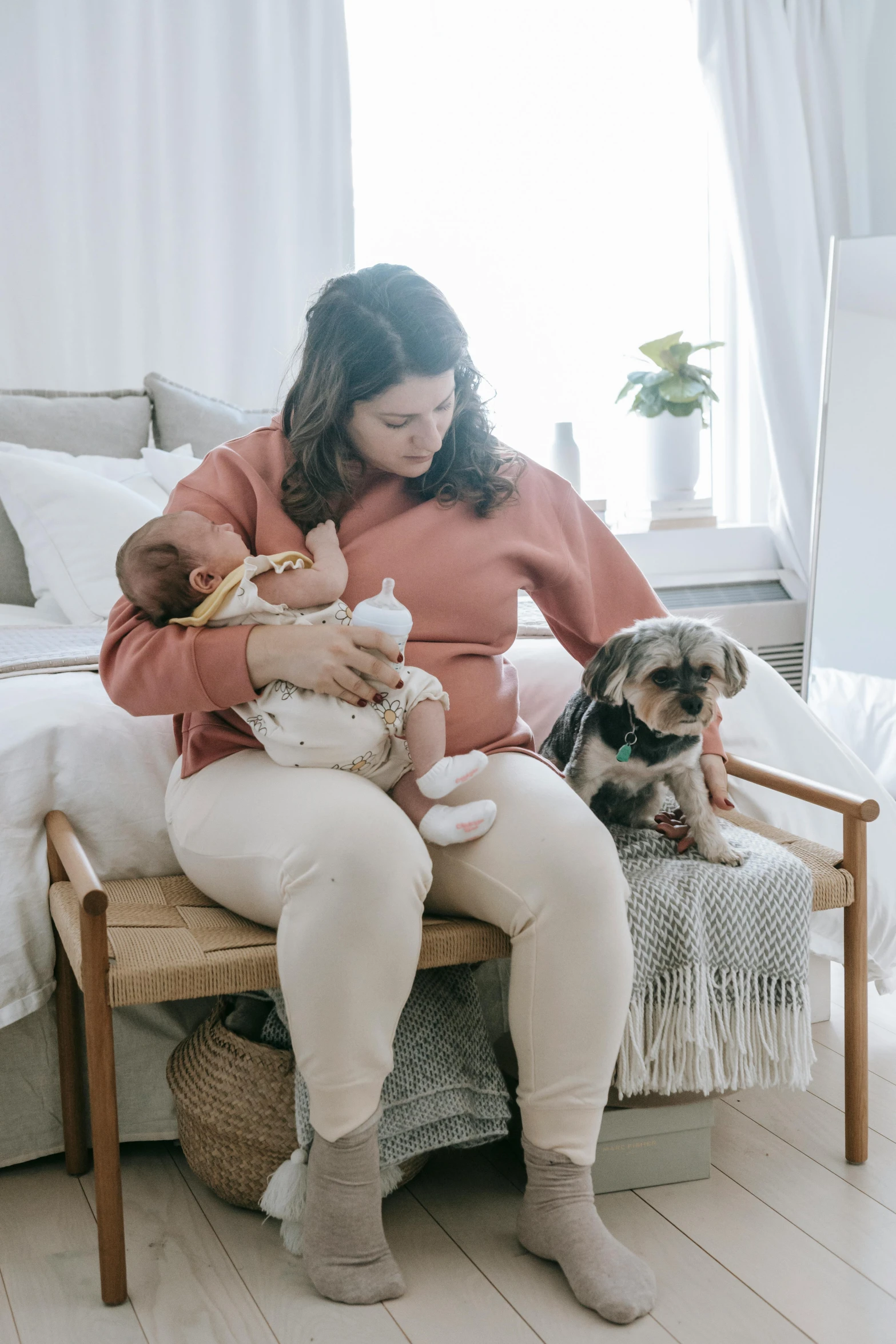 a woman sitting on a chair holding a baby and a dog, flatlay, profile image, sitting on a bed, comfy chairs