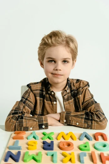 a young boy sitting at a table with a wooden puzzle, trending on pexels, mannerism, posing with crossed arms, blonde hair and large eyes, 15081959 21121991 01012000 4k, pastel'