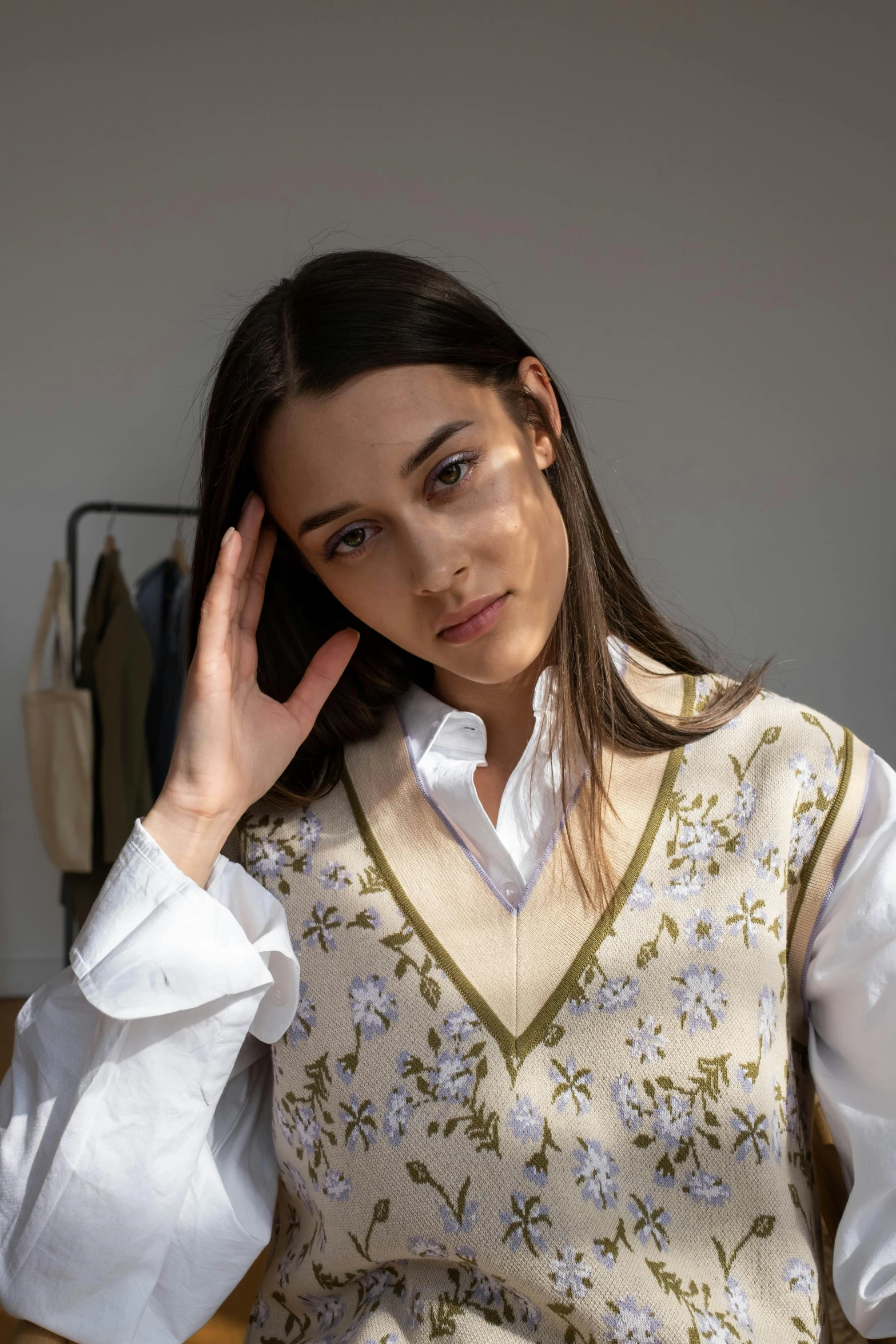 a woman sitting in a chair with her hand on her head, by Nina Hamnett, trending on unsplash, renaissance, flower butterfly vest, wearing a white button up shirt, model is wearing techtical vest, floral embroidery