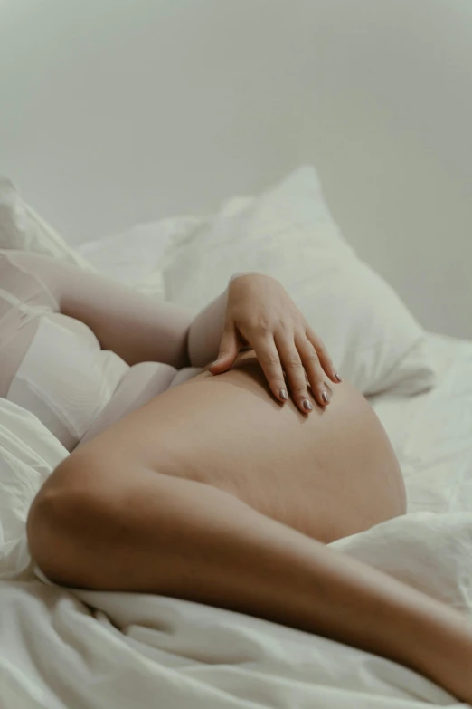 a pregnant woman laying on top of a bed, inspired by Elsa Bleda, trending on pexels, silicone skin, bum, white body, 2030s