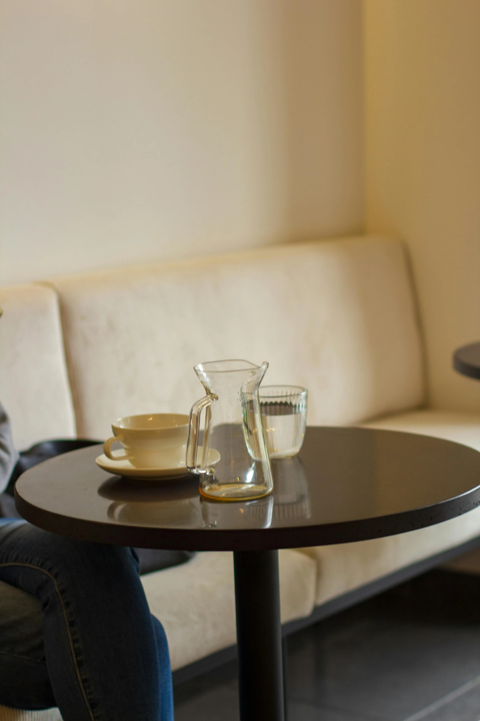 a woman sitting at a table with a cup of coffee, lounge, superior, square, taken in the late 2010s