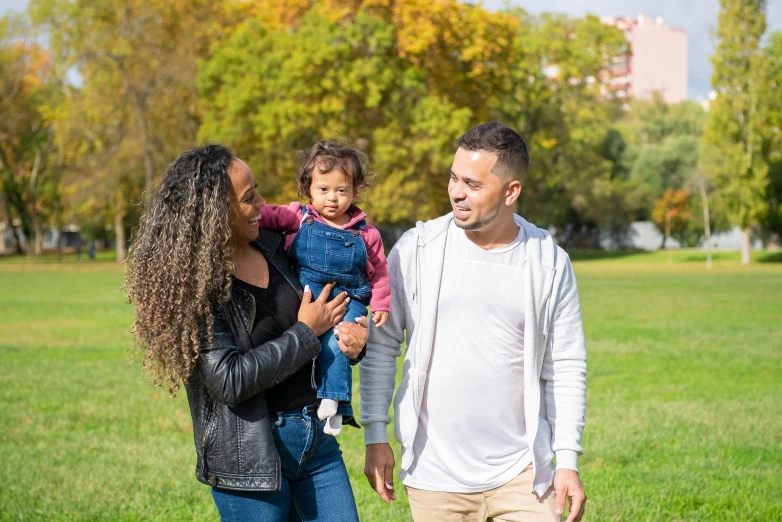 a man and woman holding a child in a park, profile image, looking confident, square, hispanic