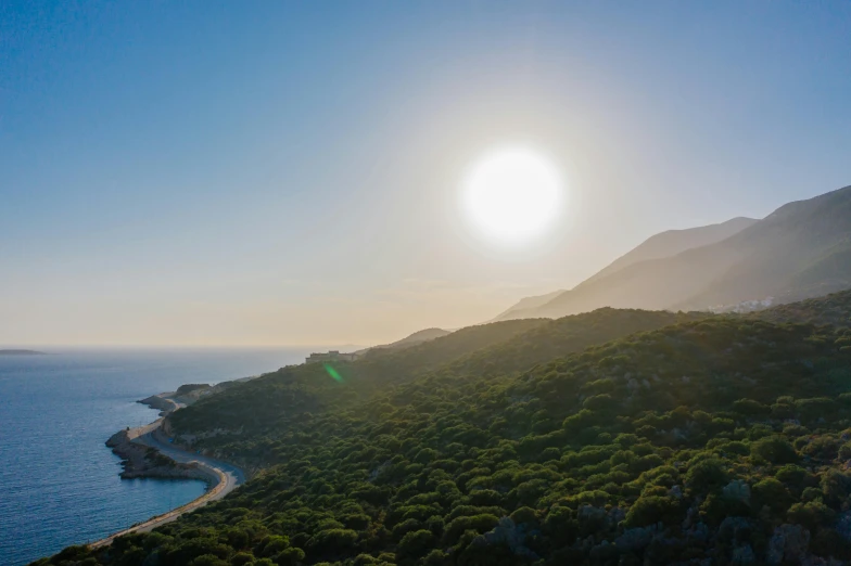 a large body of water next to a lush green hillside, by Exekias, unsplash contest winner, sun rising, pathos, coastline, isomeric view