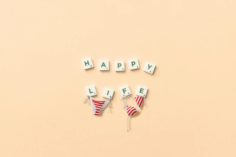 wooden letters spelling happy life on a pink background, by Emma Andijewska, unsplash, figuration libre, tiny bikini, society 6, panties, holiday season