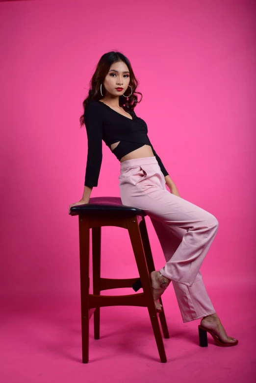 a woman sitting on top of a wooden stool, by Basuki Abdullah, pink studio lighting, pants, 15081959 21121991 01012000 4k, concept photoset