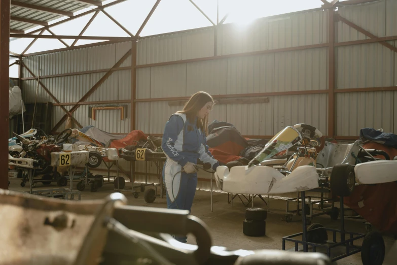 a woman working on a car in a garage, unsplash, process art, wearing human air force jumpsuit, belongings strewn about, documentary footage, hangar