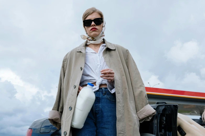 a woman standing in the back of a truck holding a bottle of milk, by Tobias Stimmer, trending on pexels, renaissance, wearing trenchcoat, lara stone, fashion week, loose - fitting blouses